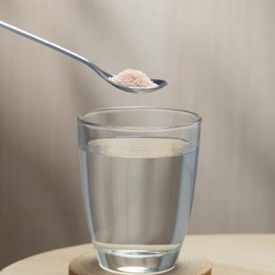 Mineral salt being measured into a glass of water, one of the hydration formats covered in module four.